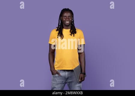 Positif afro-gars cool tenant un ordinateur portable sur violet Banque D'Images