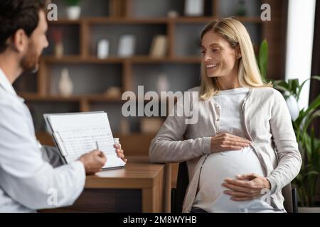 Médecin de sexe masculin montrant le presse-papiers avec les résultats des tests médicaux à la patiente enceinte Banque D'Images
