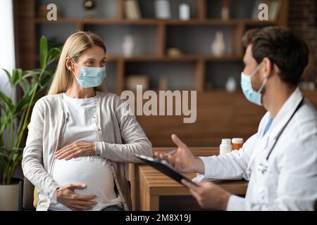 Jeune femme enceinte portant un masque facial ayant un contrôle avec un médecin thérapeute Banque D'Images