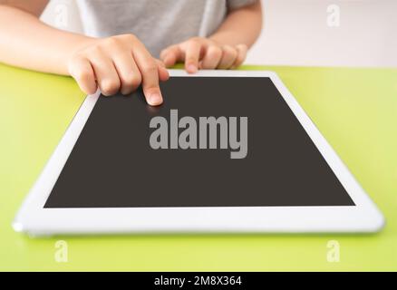 Photo d'un petit enfant à l'aide d'une tablette numérique avec un ordinateur tablette sur fond vert avec espace de copie. Banque D'Images