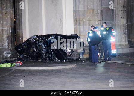 Berlin, Allemagne. 16th janvier 2023. Une voiture détruite se trouve entre deux piliers de la porte de Brandebourg, tandis que des policiers se tiennent à côté de l'épave. Une voiture s'est écrasée dans un pilier de la porte de Brandebourg à Berlin. A l'intérieur de la voiture, les pompiers ont trouvé un homme mort, a déclaré un porte-parole de la police tôt lundi matin. Credit: Annette Riedl/dpa/Alay Live News Banque D'Images