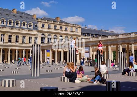 Paris: Personnes appréciant les colonnes de Buren (les deux plateaux) par Daniel Buren au cours d'Honneur du Palais Royal, Paris, France Banque D'Images