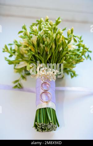 une paire d'anneaux dorés se trouve sur le bouquet de fleurs de mariage de la mariée Banque D'Images