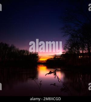 Les étoiles et les couleurs du coucher de soleil comme elles apparaissent sur la rivière blanche dans le comté de Jackson, DANS. Vénus peut se refléter dans l'eau et au-dessus des arbres. Banque D'Images