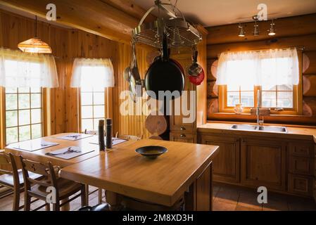 Armoires en bois de pin, table à manger et îlot dans la cuisine à l'intérieur de la maison en rondins de style cottage scandinave. Banque D'Images