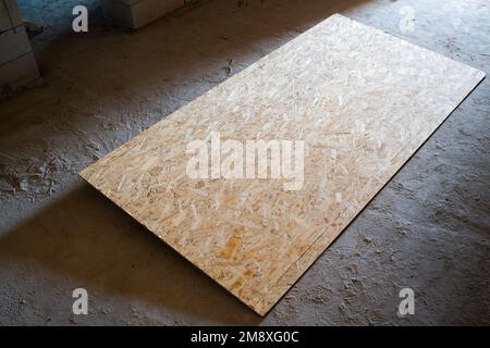 Une feuille rectangulaire solide de toron orienté repose sur le sol d'un chantier de construction. Panneau OSB sur sol en béton, vue du dessus Banque D'Images