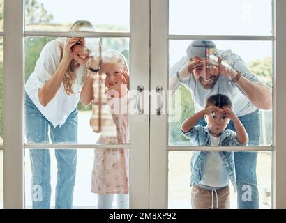 Couple curieux avec de petits enfants debout et de piquant dans leur nouvelle maison. Une famille caucasienne souriante et excitée qui regarde et vérifie sa maison Banque D'Images