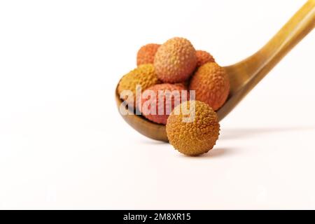 Lychees frais dans une cuillère en bois isolée sur fond blanc Banque D'Images