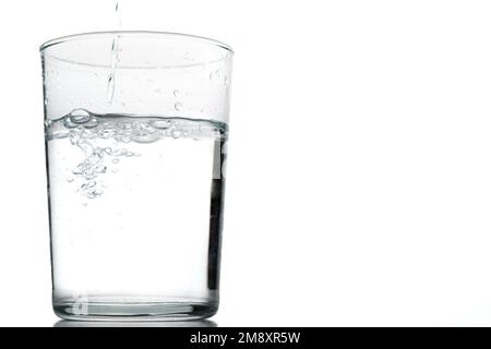 Gros plan d'un verre en mouvement d'eau cristalline isolée sur un fond blanc Banque D'Images