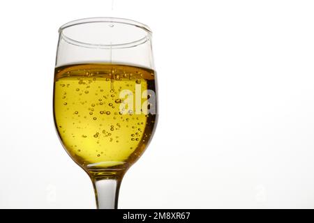 Gros plan d'une tasse en verre avec de l'huile d'olive extra vierge avec des bulles sur fond blanc Banque D'Images