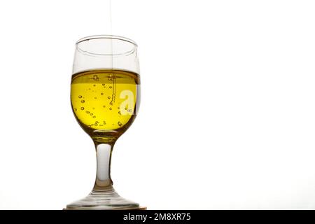 Gros plan d'une tasse en verre avec de l'huile d'olive extra vierge avec des bulles sur fond blanc Banque D'Images