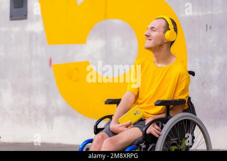 Portrait d'une personne handicapée vêtue de jaune en fauteuil roulant à l'écoute de musique Banque D'Images