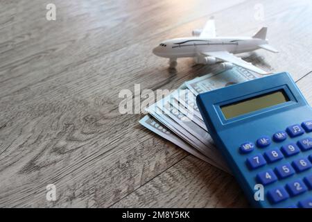 Jouet avion, argent et calculatrice sur table en bois avec espace de copie. Concept de voyage et de transport Banque D'Images