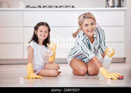 Portrait d'une jeune femme caucasienne souriante s'agenouillant et frottant le sol avec sa fille. Adorable petite fille aidant sa mère à faire des travaux ménagers Banque D'Images