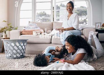 Les joies d'avoir une fille plus âgée. une adorable petite fille jouant avec sa petite sœur tandis que leur mère les regarde à la maison. Banque D'Images