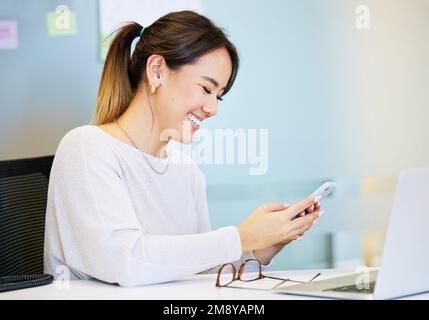 Où nous rencontrons-nous ? une jeune femme d'affaires attirante assise seule au bureau et utilisant son téléphone portable. Banque D'Images