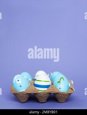 pâques coloré fait à la main oeufs bleus peints dans une boîte sur le fond perple très péri. Banque D'Images
