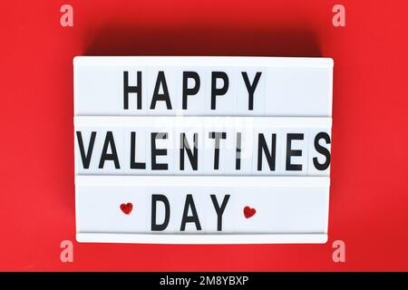 Visionneuse avec inscription Happy Valentine's Day sur fond rouge. Banque D'Images