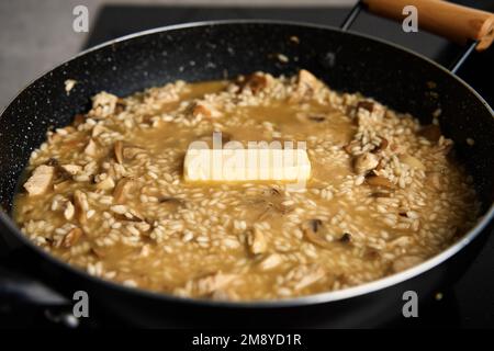 Processus de cuisson du risotto. Arborio riz et morceau de beurre dans poêle à frire dans la cuisine maison. Plat de cuisine italienne Banque D'Images