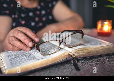 Une vieille femme lit la Bible, les mains de près. Banque D'Images