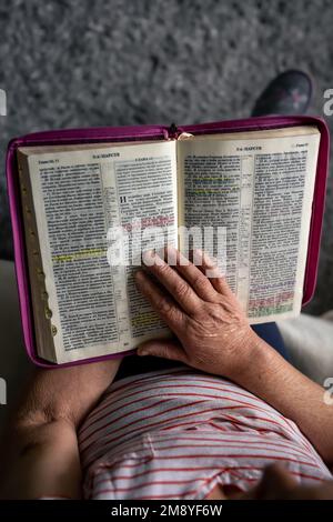Une vieille femme lit la Bible, les mains de près. Banque D'Images