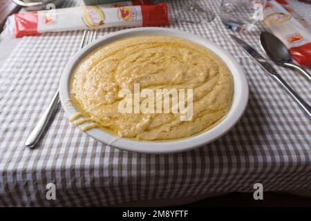 Vue rapprochée d'une portion de polenta concia, un repas traditionnel servi dans la région alpine de l'Italie Banque D'Images