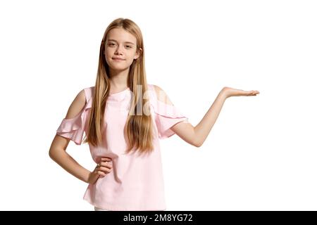 Portrait studio d'une belle fille blonde adolescente dans un t-shirt rose posant isolé sur fond blanc. Banque D'Images