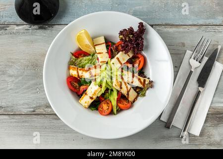 Salade de tomates et de fromage halloumi sur une table en bois Banque D'Images