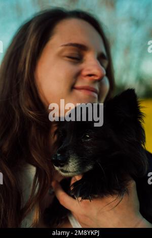 Une femme enceinte avec un petit chien noir dans la nature. Champ de colza Banque D'Images