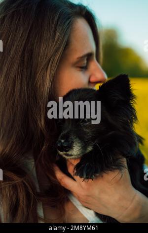 Une femme enceinte avec un petit chien noir dans la nature. Champ de colza Banque D'Images