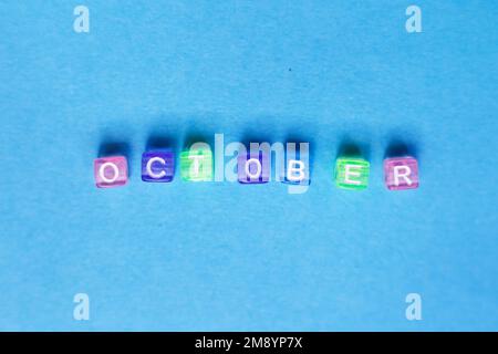 inscription octobre faite par des cubes en plastique multicolore sur fond bleu Banque D'Images