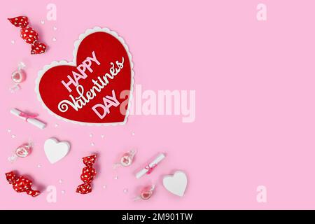 Plat de Saint-Valentin avec coeur avec texte « Happy Valentine's Day », bonbons et ornements de coeur sur fond rose avec espace de copie Banque D'Images