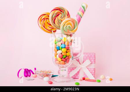 Bonbons colorés dans une tasse sur une table sur fond clair. Grands sucettes tournantes. Concept créatif d'un pot rempli de délicieux bonbons de la Banque D'Images