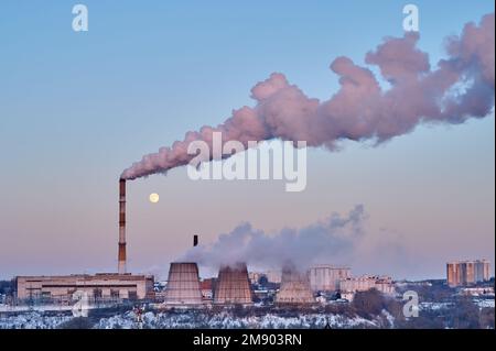 Vue sur la centrale thermique au coucher du soleil et sur la lune dans le ciel. Fumée blanche épaisse provenant des tuyaux Banque D'Images