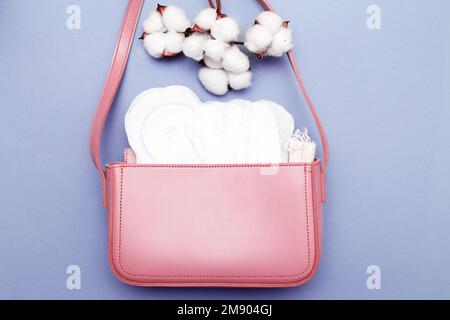 tampons, protège-slips hygiéniques, coussinets hygiéniques féminins dans un sac cosmétique rose pour femmes sur fond violet. concept d'hygiène et de soins de santé pour les femmes Banque D'Images