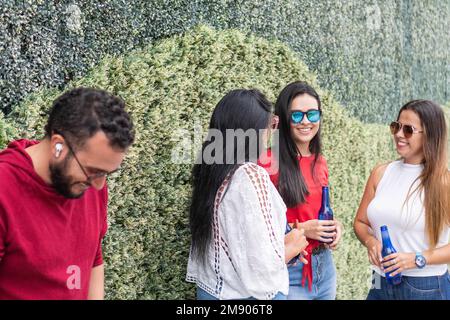 Homme dans des lunettes de soleil à la mode près d'amis multiethniques parlant dans la rue Banque D'Images