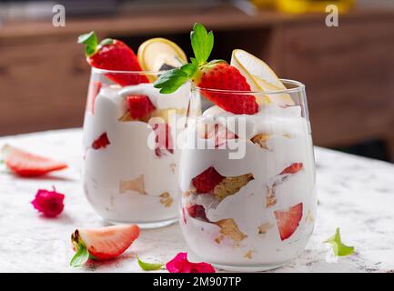 Dessert sucré en verre avec biscuit, fruits aux baies et crème fouettée. Banque D'Images