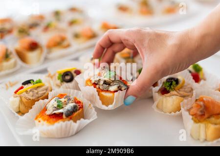 Gros plan de la main femelle tenant le canape. Concept de repas sous forme de buffet. Banque D'Images