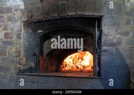 Ancien four à pain utilisé avec les flammes du feu, bakehouse du 17th siècle au Weald and Downland Living History Museum, West Sussex, Angleterre, Royaume-Uni Banque D'Images