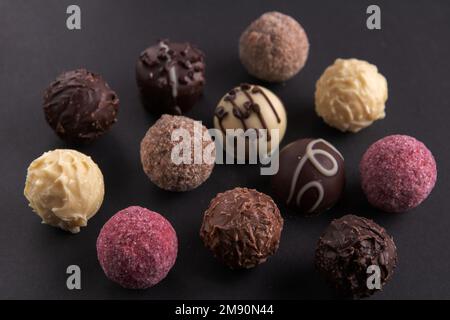 bonbons photo chocolat de différentes couleurs se trouvant côte à côte sur un fond noir Banque D'Images