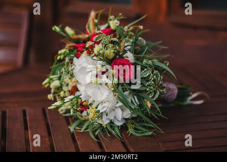 le bouquet de mariage de style rustique se trouve sur le parquet avec des roses et des pâquerettes Banque D'Images