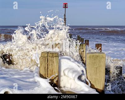 De grandes vagues se brisant sur des groynes en bois sur la plage de Walcott, dans le nord du Norfolk après une tempête qui s'apaise Banque D'Images