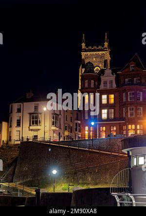 En regardant vers l'église Cromer et les rues des marins, Cromer Pier dans le nord de Norfolk la nuit, lors d'une soirée d'automne froide avec une lueur chaleureuse provenant de bâtiments éclairés. Banque D'Images