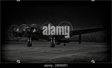 Image monochrome du bombardier AVRO Lancaster 'Just Jane', actuellement en cours de restauration au Lincolnshire Aviation Heritage Centre avec des moteurs fonctionnant après la tombée de la nuit. Banque D'Images