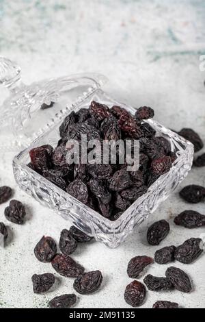 Raisins noirs séchés sur fond de pierre. Raisins secs dans un bol en verre. Variétés de noix. Une alimentation saine. gros plan Banque D'Images