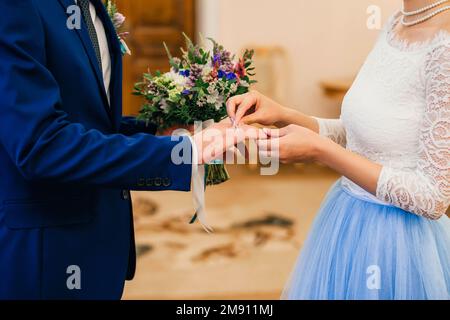 la mariée porte un anneau d'or sur le doigt du marié lors de la cérémonie de mariage Banque D'Images