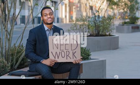 Stressé bouleversé triste désespéré étudiant ethnique désespéré tenant une affiche besoin de travail. Un homme d'affaires afro-américain en faillite a perdu des affaires pendant Banque D'Images