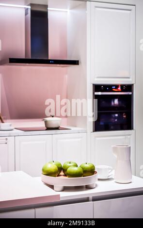 Un détail d'une cuisine moderne blanche avec quelques pommes vertes dans un bol Banque D'Images
