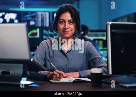 Portrait de jeune femme d'affaires adulte réussie, secrétaire, directeur des ventes, consultant, en chemise officielle, assis au bureau avec un ordinateur portable, regardant l'appareil photo, souriant. Photo de haute qualité Banque D'Images