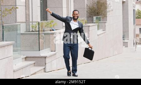 Joyeux homme d'affaires afro-américain millénaire barbu homme joyeux dansant dehors dans la ville célébrant vendredi professionnel de réalisation d'affaires Banque D'Images